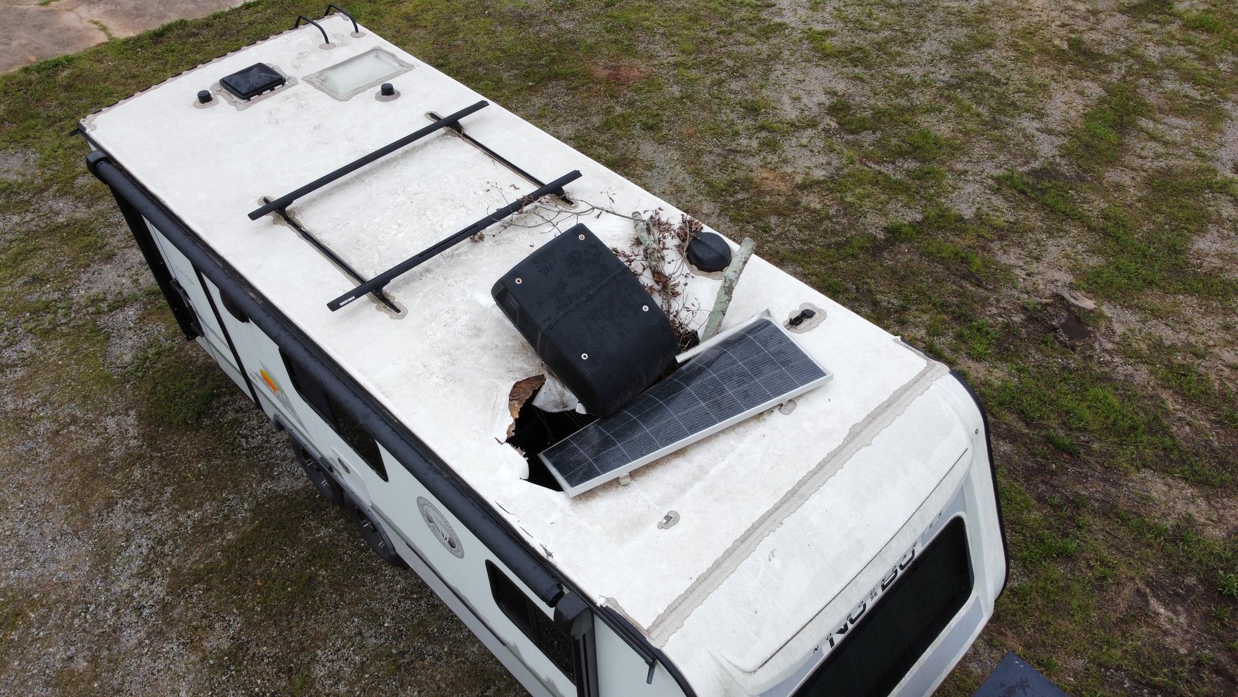 Tree branch that crashed onto an RV roof, punching a hole in the membrane and knocking loose a solar panel